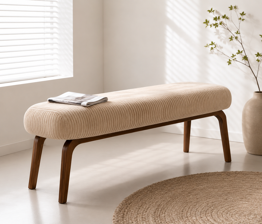 Amance Bench in sand ribbed upholstery on splayed walnut legs, in a bright room beside a round jute rug