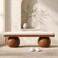 Boule Bench seen straight on: a cream cushion in a walnut tray, carried on two turned wooden spheres, below an arched wall niche