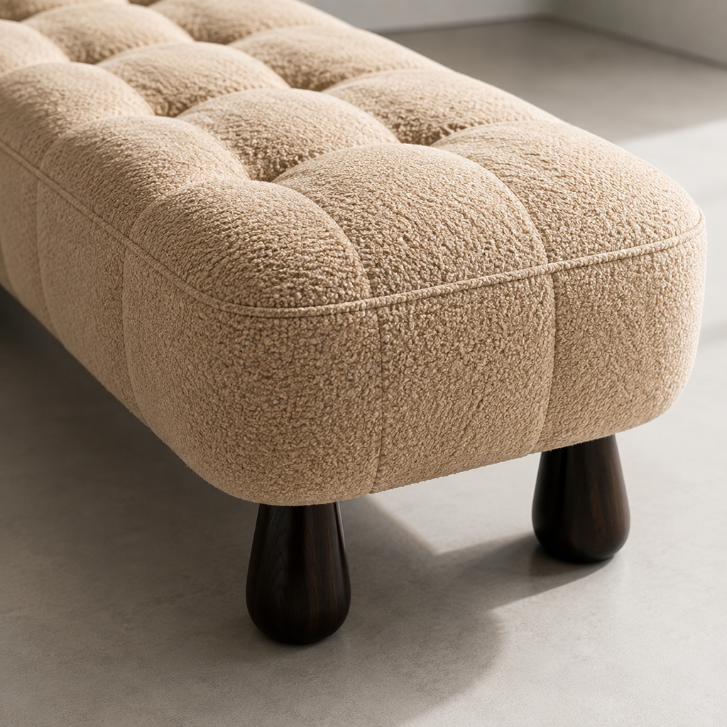 Close view of the Capiton Bench in camel: the tufted grid, the piped edge and one dark turned leg