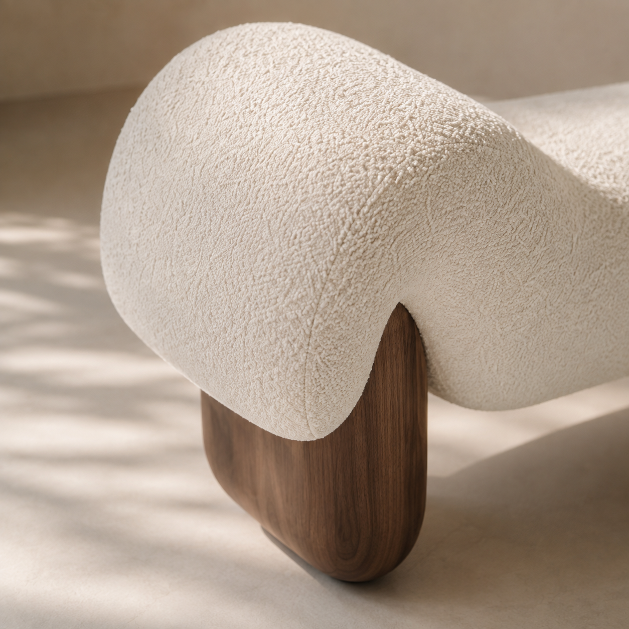 Close view of the Dune Bench, the looped bouclé pile meeting the grain of the walnut foot