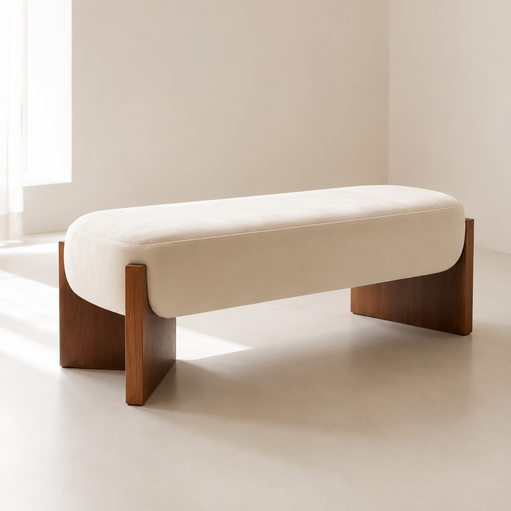 Ecrin Bench in cream, a rounded cushion cradled between two walnut slab legs, in a sunlit room
