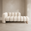 Godron Bench in cream bouclé, the fluted seat running from a low backrest to an open end on a brass-toned rail