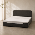 Liseré Bed in charcoal, the piped headboard rising behind a deep upholstered base