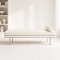 Leman Bench seen straight on: an ivory channel-tufted cushion with a bolster at one end, on a polished steel frame