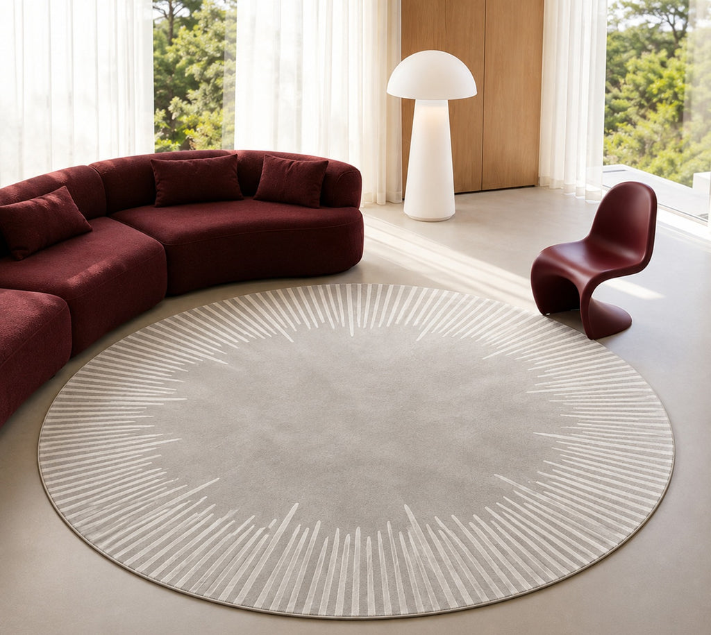 Ondine Rug, round, in grey and ivory beside a curved deep red sofa in a bright room