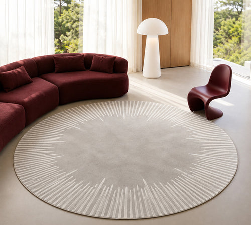 Ondine Rug, round, in grey and ivory beside a curved deep red sofa in a bright room