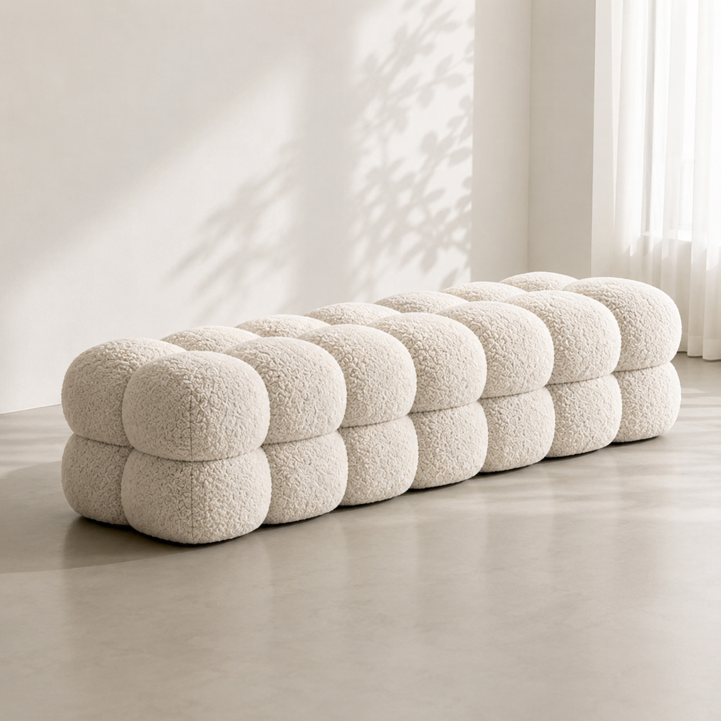 Perle Bench: two rows of boucle spheres stacked into a long seat, on a pale concrete floor with leaf shadows on the wall
