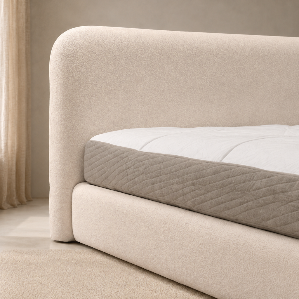 Close view of the Songe Bed, the headboard's rounded corner and the seam where it meets the platform