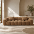 Tonneau Sofa in caramel bouclé seen straight on, the channelled seat running between two rolled arms