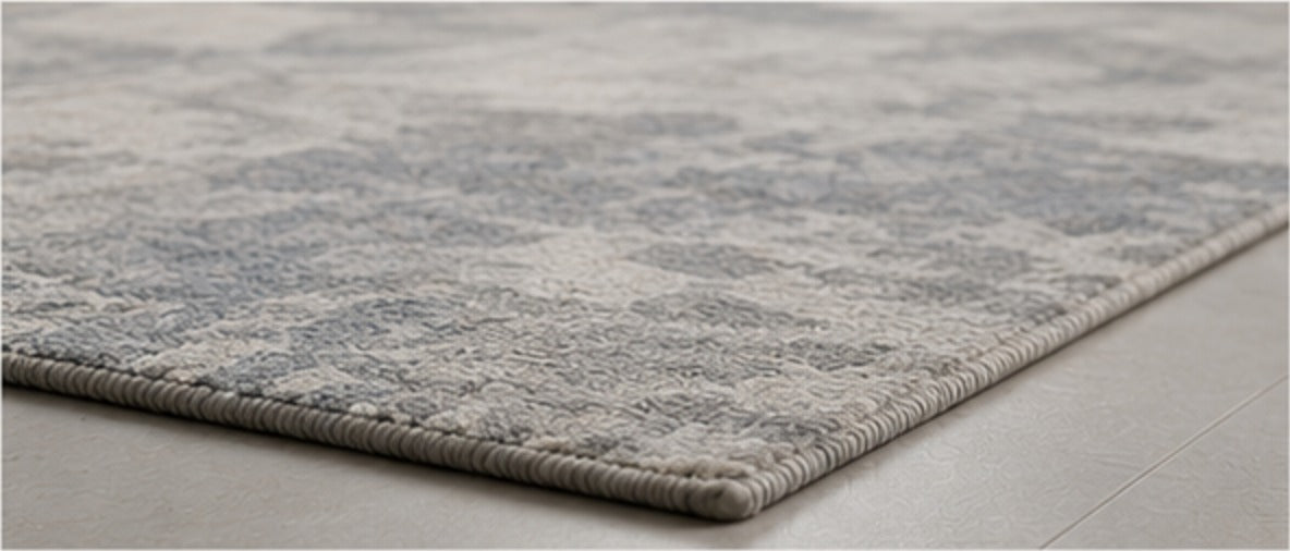 Close view of the Valori Rug's woven edge on a pale stone floor