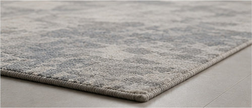Close view of the Valori Rug's woven edge on a pale stone floor