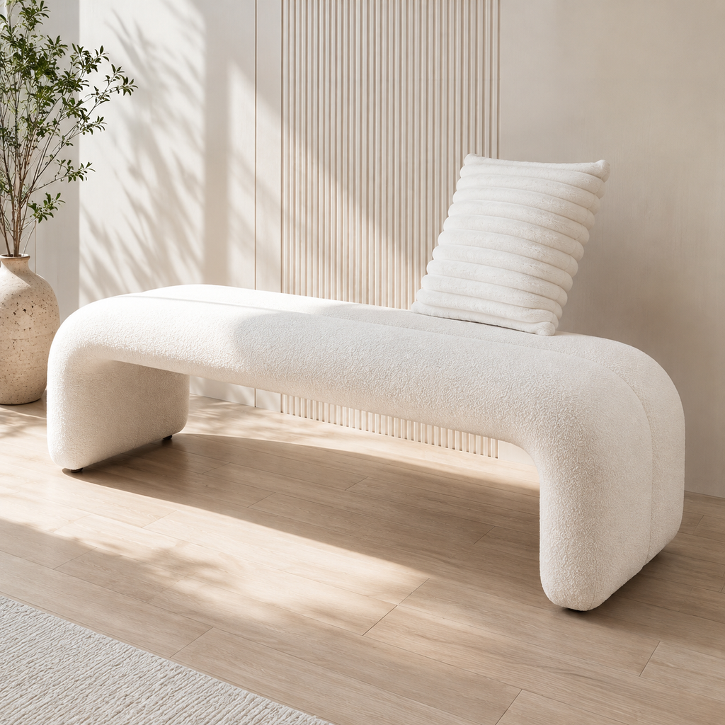 Voute Bench in ivory looped upholstery, its ends curving down to the floor, in sunlight beside a slatted wall